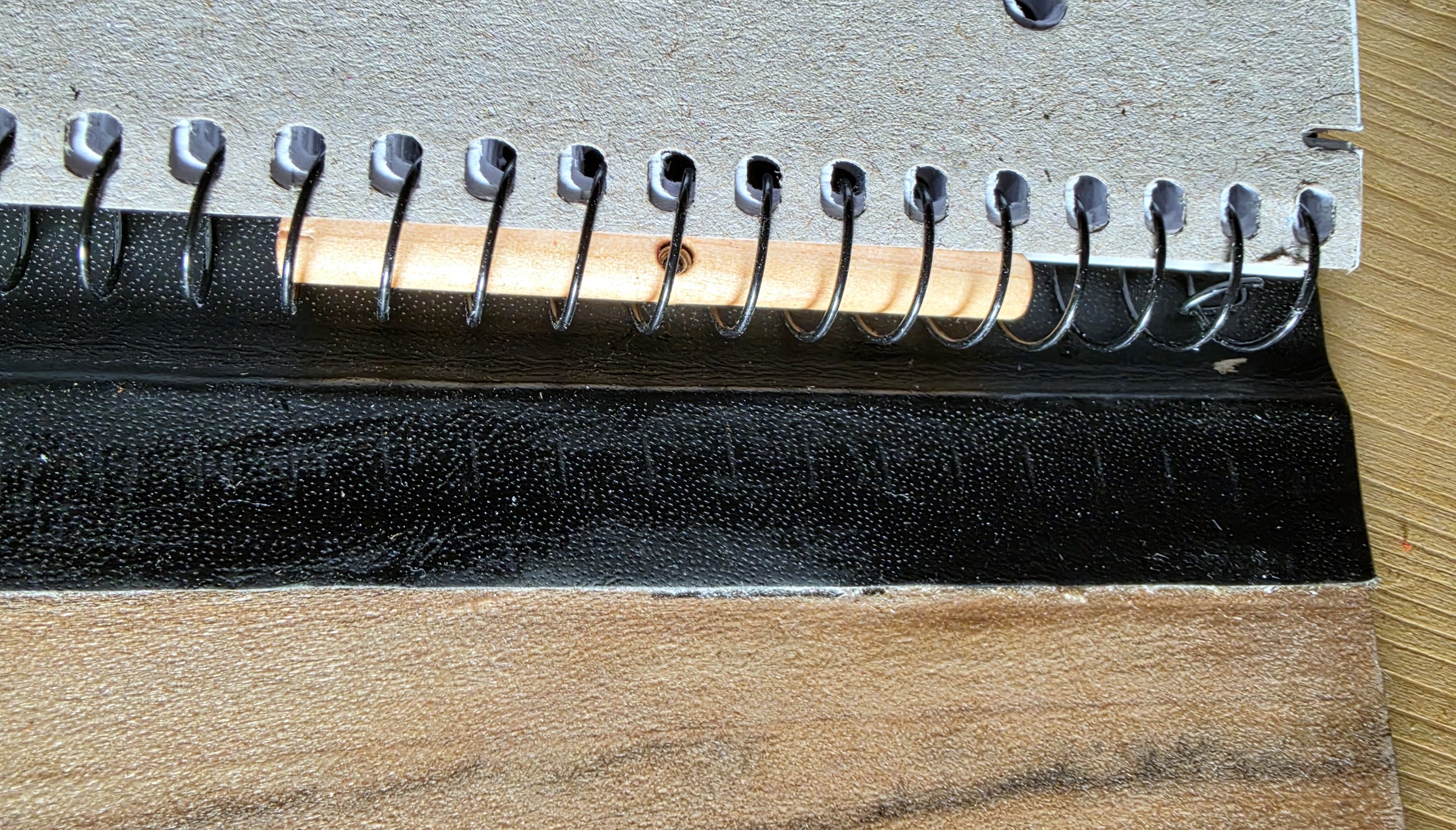 Detailansicht: Holzstab, Schraube und Spiralbindung